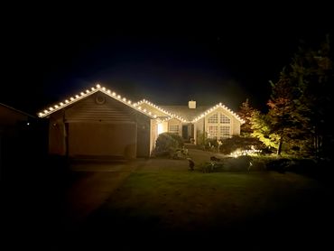 House decorated with warm white string lights outlining the roof at night.
