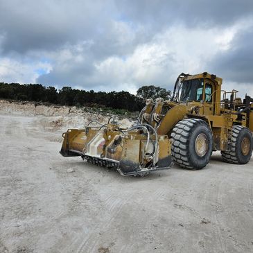 Heavy construction vehicle with attachments on a dusty site.