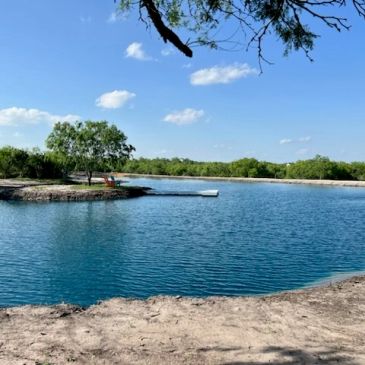 Calm lake with a dock under clear blue sky.