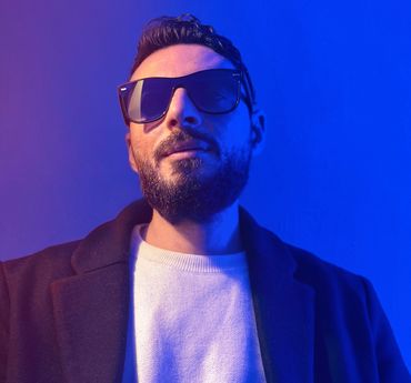 Man with sunglasses in blue and purple lighting.