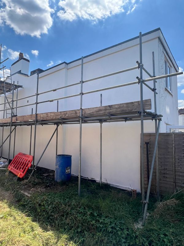 Scaffolding set up around a white building under a partly cloudy sky.
