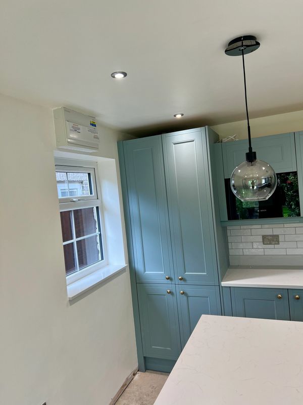 Modern kitchen corner with blue cabinets and a glass pendant light.