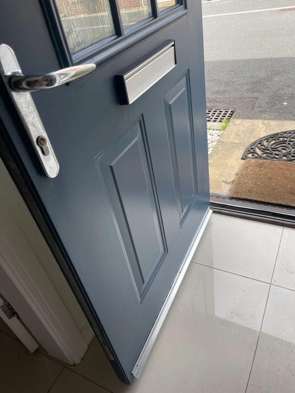 Open blue front door with silver handle and mail slot.