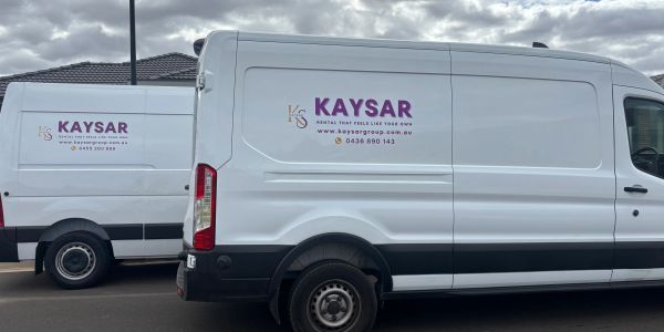 Two white vans with KAYSAR branding parked.