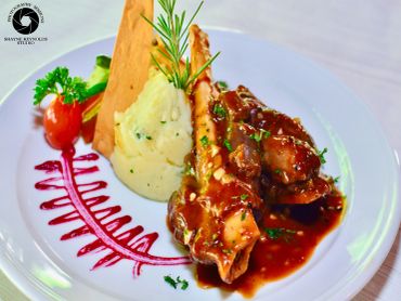 Gourmet dish with mashed potatoes, glazed meat, and fresh herbs on white plate.