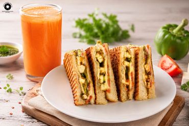 Grilled sandwiches with paneer, served with a glass of fresh orange juice.