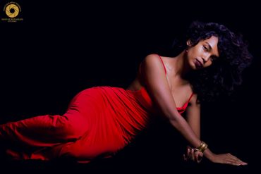 Woman in a red dress posing against a black background.
