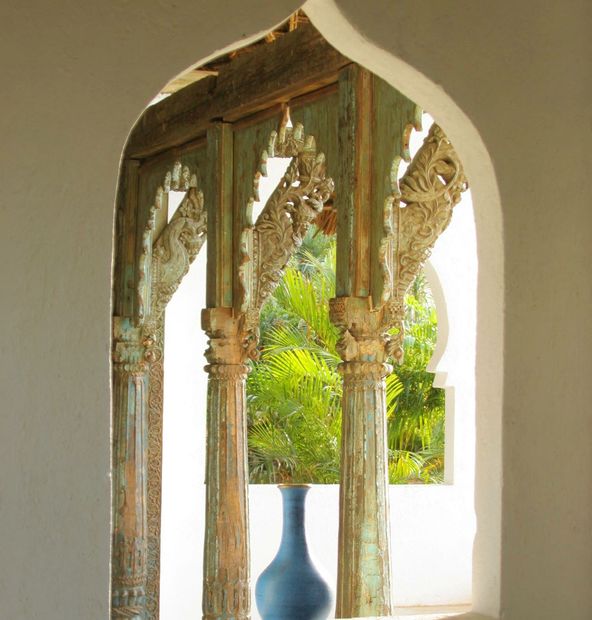 Ornate carved pillars and a blue vase framed by an arch.