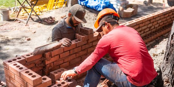 two construction workers building a wall