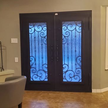 Double glass doors with intricate wrought iron designs and blue-tinted glass.