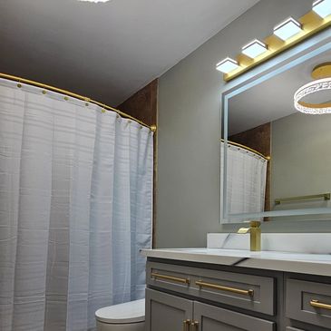 Modern bathroom with gray cabinets and gold fixtures.