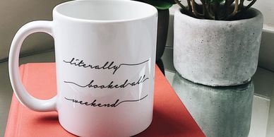 White mug with words 'Literally booked all weekend' written across it.