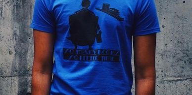A male wearing a royal blue t-shirt with the words 'So many books so little time' and an image acros