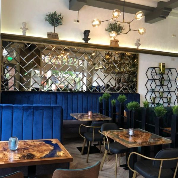 Chique restaurant met blauwe banken en houten tafels.