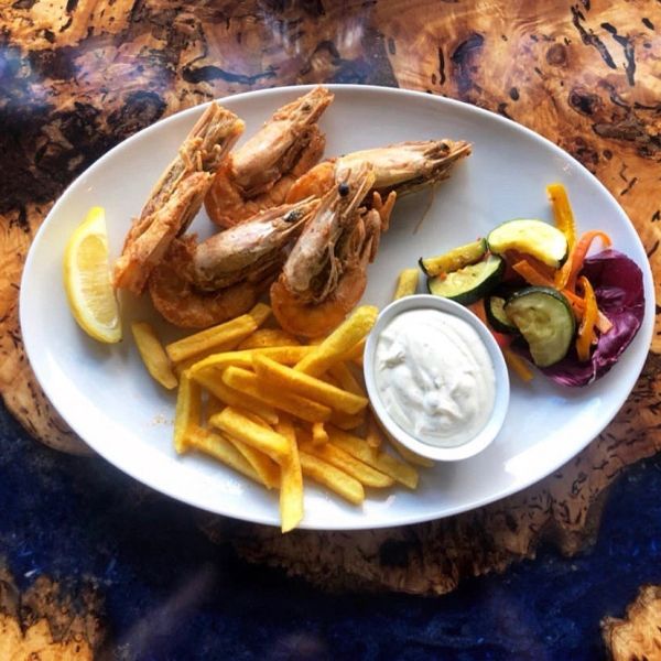 Bord met garnalen, frieten, citroen en saus.