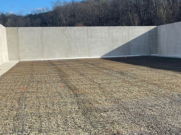 A rectangular concrete enclosure with a floor covered in gravel and a wire mesh grid.