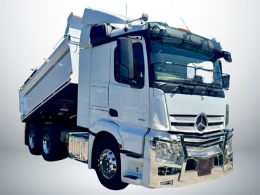 White Mercedes dump truck with chrome details.