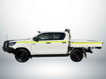 White Toyota Hilux pickup truck with a yellow stripe and black wheels.