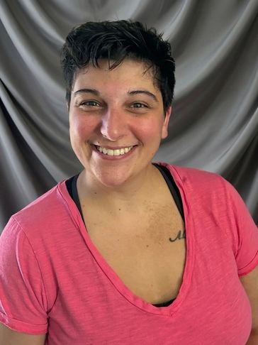 Smiling person in a pink shirt against a gray backdrop.