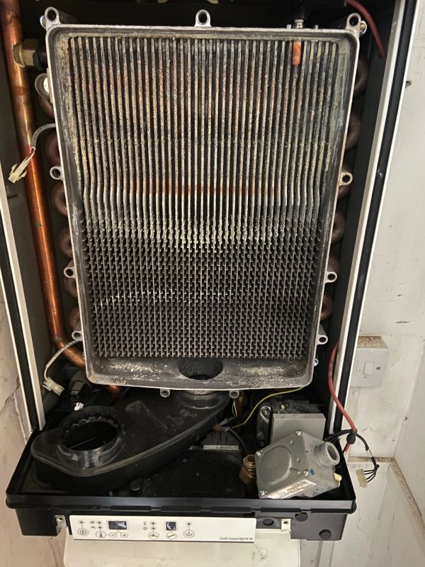 Open boiler showing internal components and heat exchanger with dust buildup.