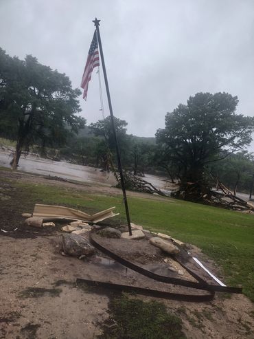 American flag flying on a bent pole in a stormy, flooded area.