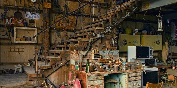Rustic workshop with wooden stairs and cluttered workbench.