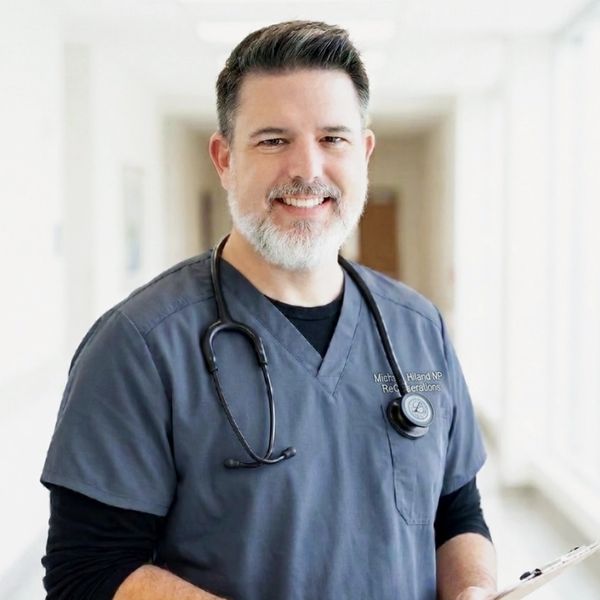 Smiling male healthcare professional in scrubs with stethoscope.