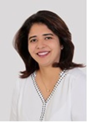 Smiling woman in white blouse with dark hair against a plain background.