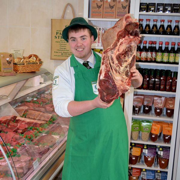 Owner of Patrick Strainge Butchers, holding a large piece of meat