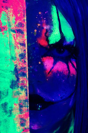 Close-up of a face with vibrant neon paint under blacklight.