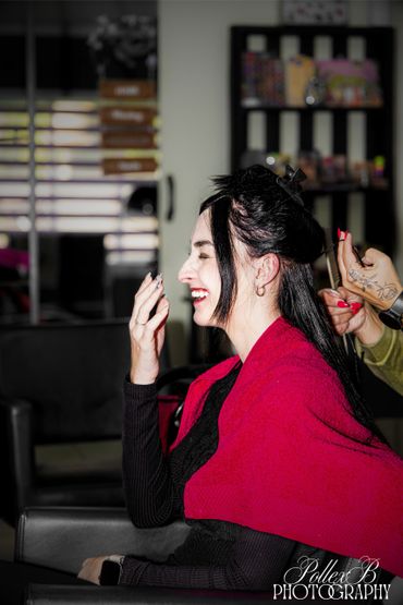 Woman laughing while getting her hair styled at a salon.