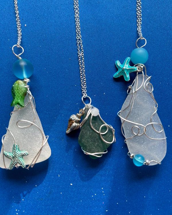 Three sea-themed pendants with wire wrapping and ocean charms on silver chains.