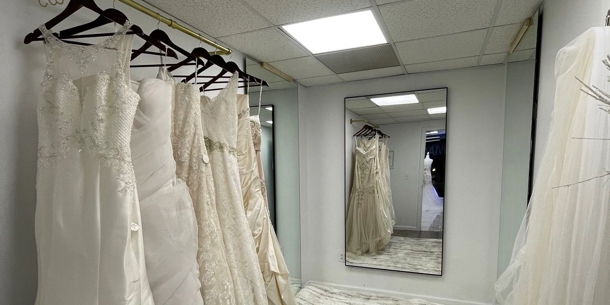 Elegant wedding dresses hanging on a rack in a bridal boutique fitting room.