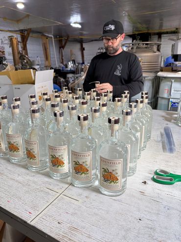 Man inspecting bottles of Edenfield Small Batch Appalachian Gin at a distillery.