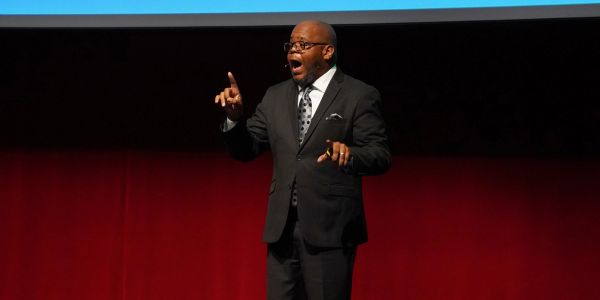 Man in suit passionately speaking on stage.