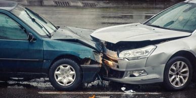 Two cars involved in a head-on collision on a wet road.
