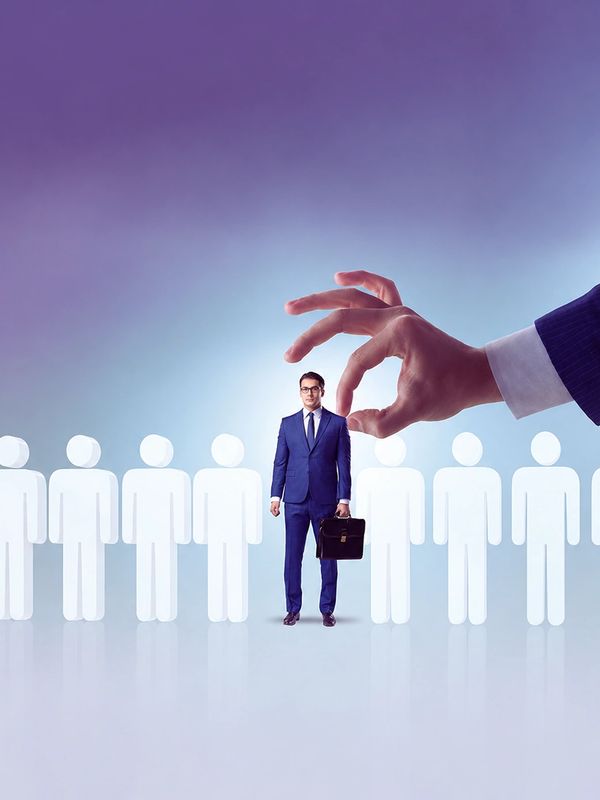 A businessman is being selected among many candidates by a giant hand.