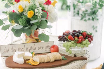 A charming fruit and cheese platter with a floral centerpiece and a 'happily ever after' sign.