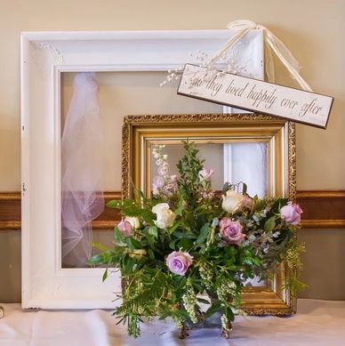 Decorative floral arrangement with picture frames and a 'happily ever after' sign.