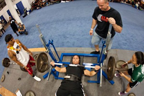 a person lifting weight under a supervision