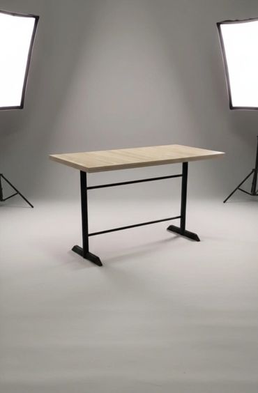 Simple wooden table with black metal legs in a studio setup.