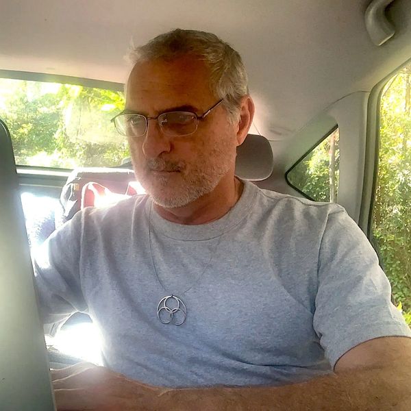 Guy Lane works on his computer in Motel Prius wearing a Quendant.