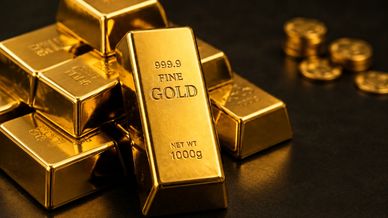 Stack of shiny gold bars and coins on a dark surface.