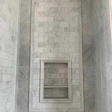 Elegant marble tiled wall with a recessed shelf in a bathroom.