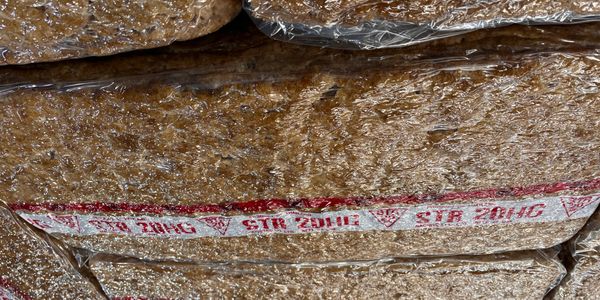 Stacked bags of brownish material wrapped in plastic with a label.