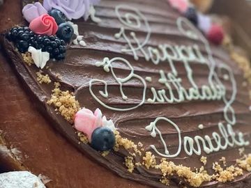 Close-up of a chocolate birthday cake with berries and cream.