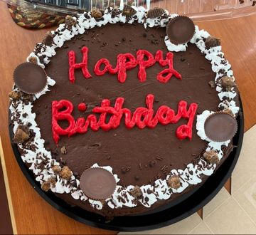 Chocolate birthday cake with red lettering and peanut butter cups.