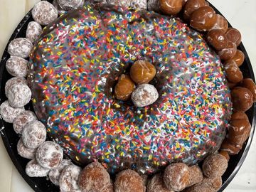 Sprinkles-covered donut surrounded by various donut holes.