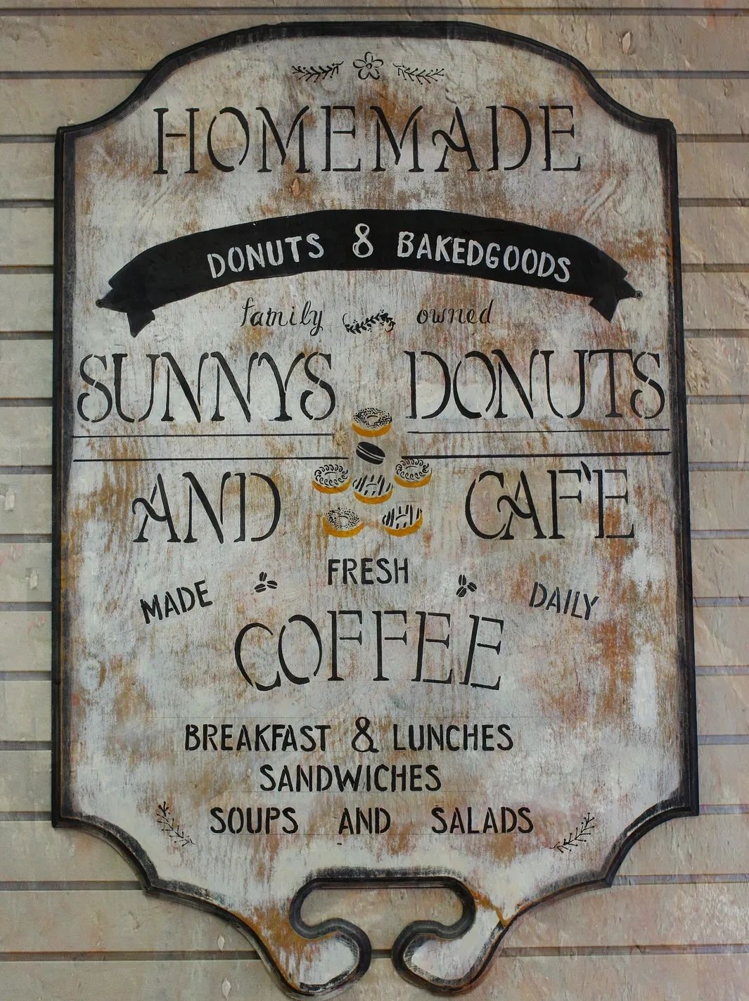 Rustic sign for Sunny's Donuts and Cafe offering homemade donuts and coffee.
