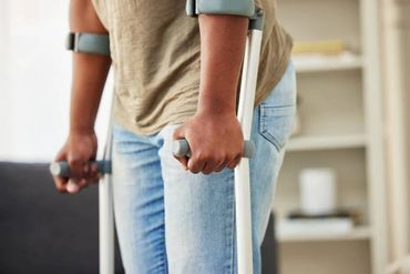 Person using crutches for support, standing indoors.